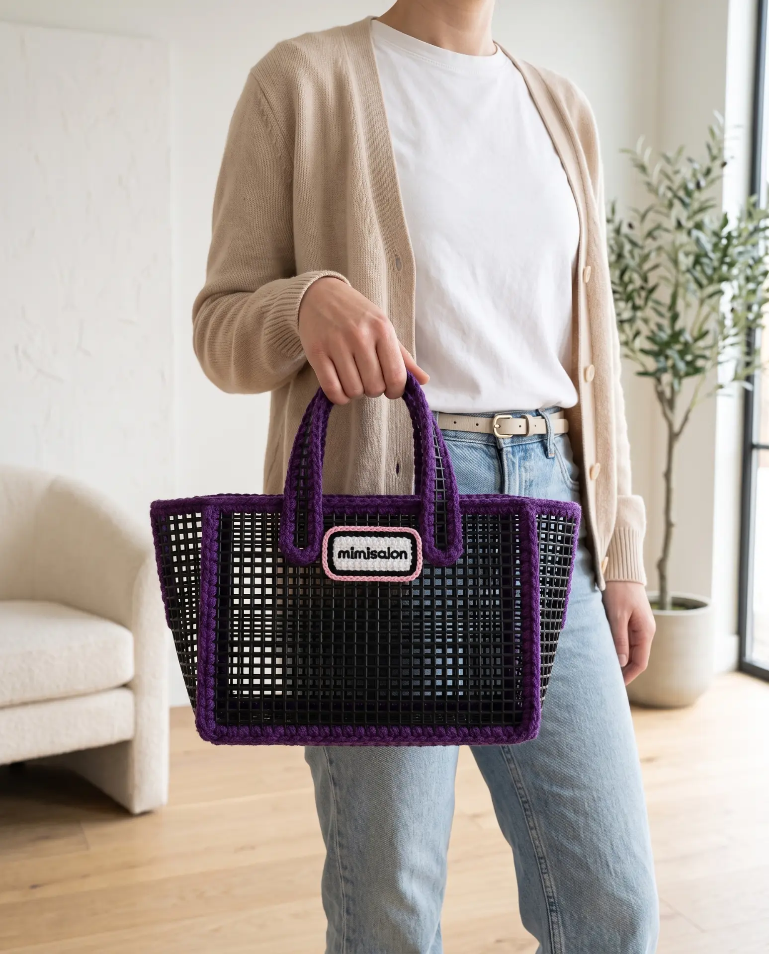 Black mesh tote with purple crochet trim held in a bright living room